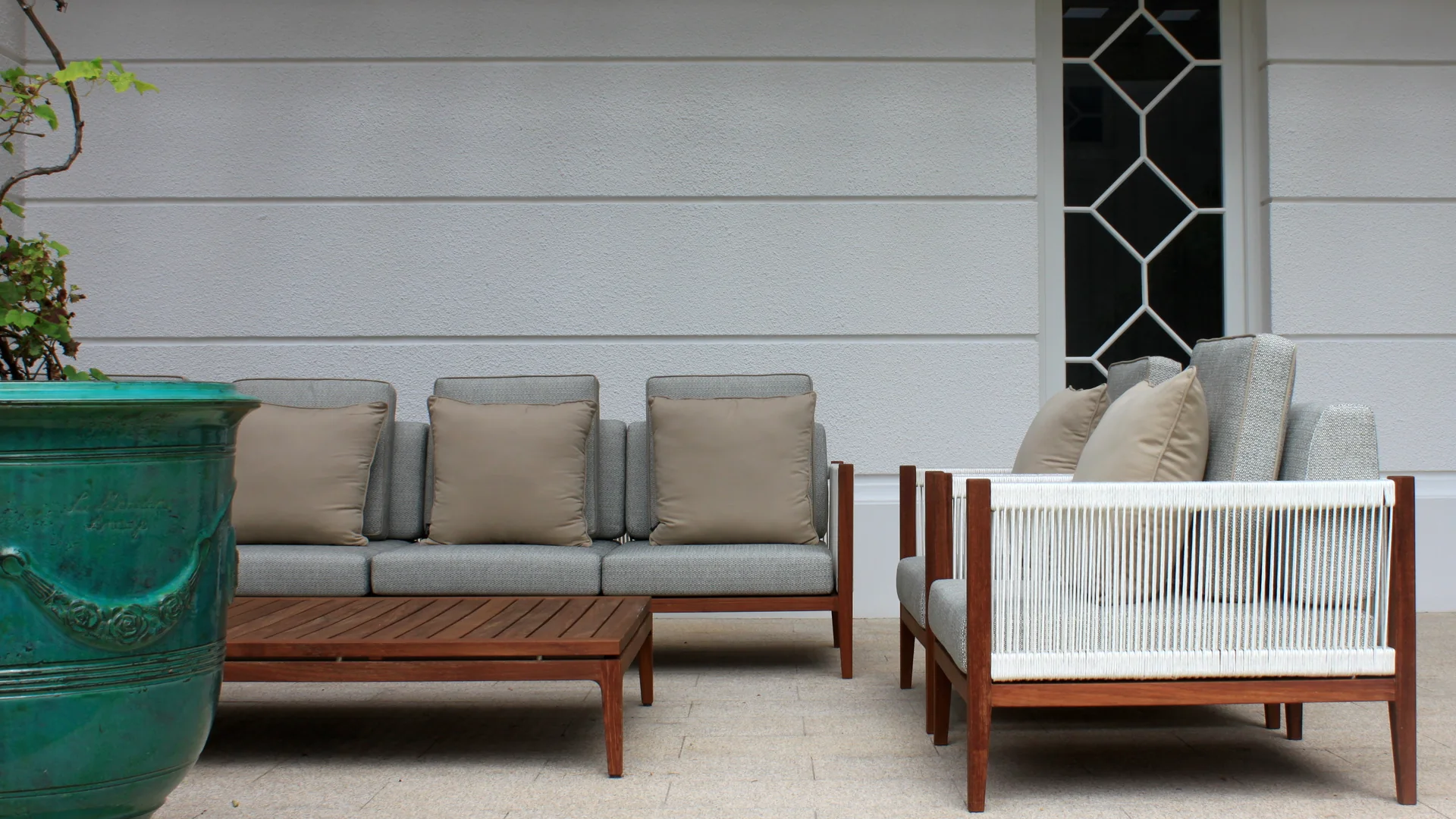 Bespoke hardwood outdoor sofa and low table with soft grey cushions against a pale limewash wall